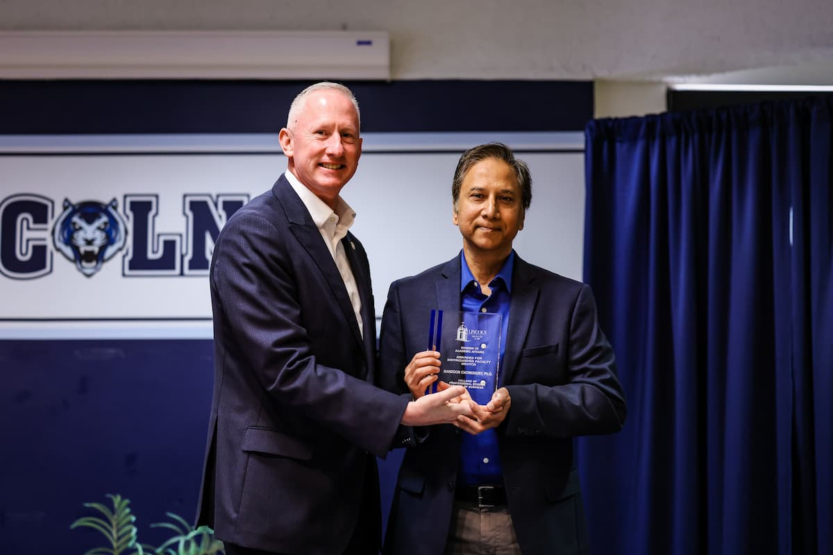 President Moseley and Manzoor Chowdhury stand while holding a plaque.