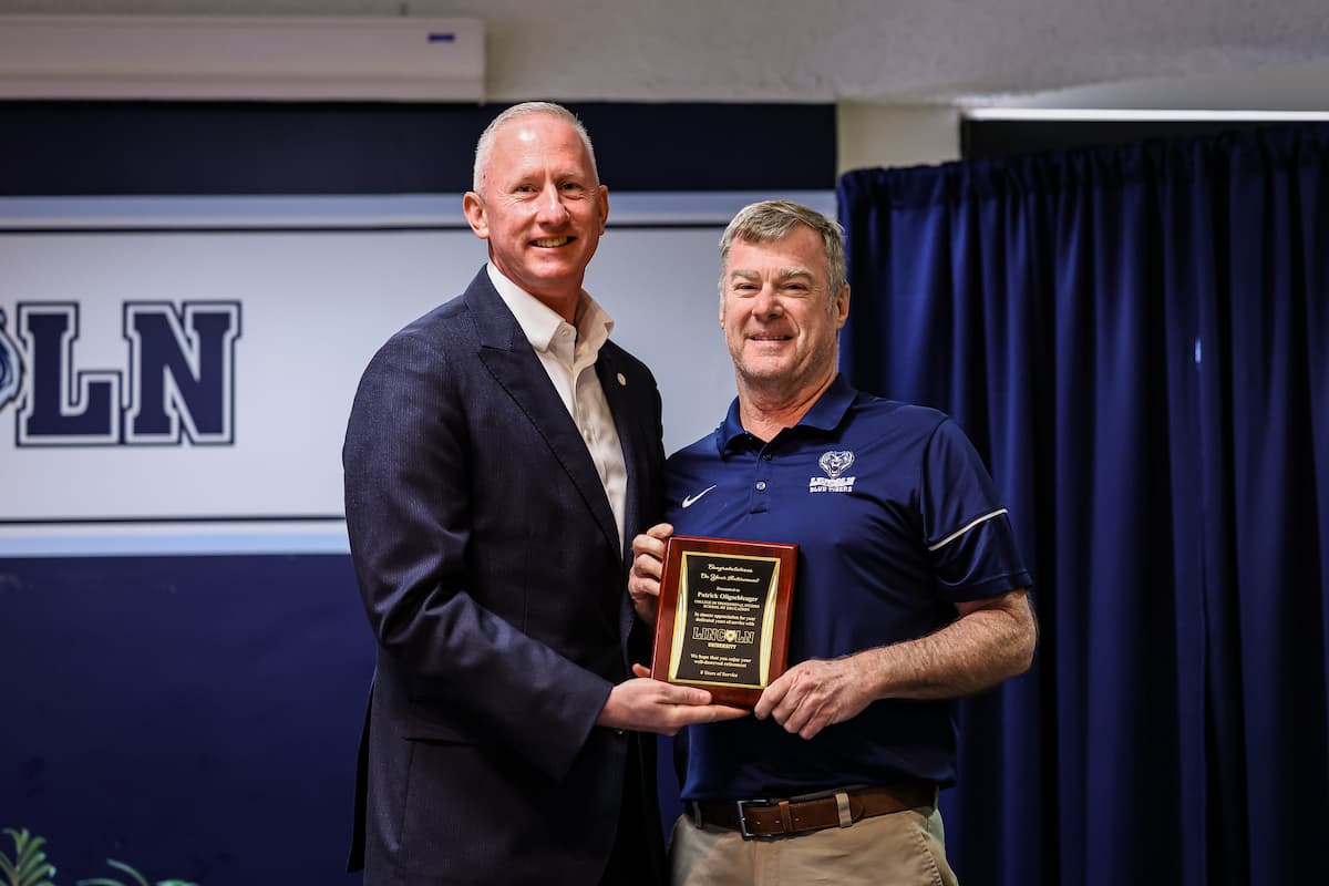 President Mosley and Patrick Oligschlaeger stand while holding a plaque.