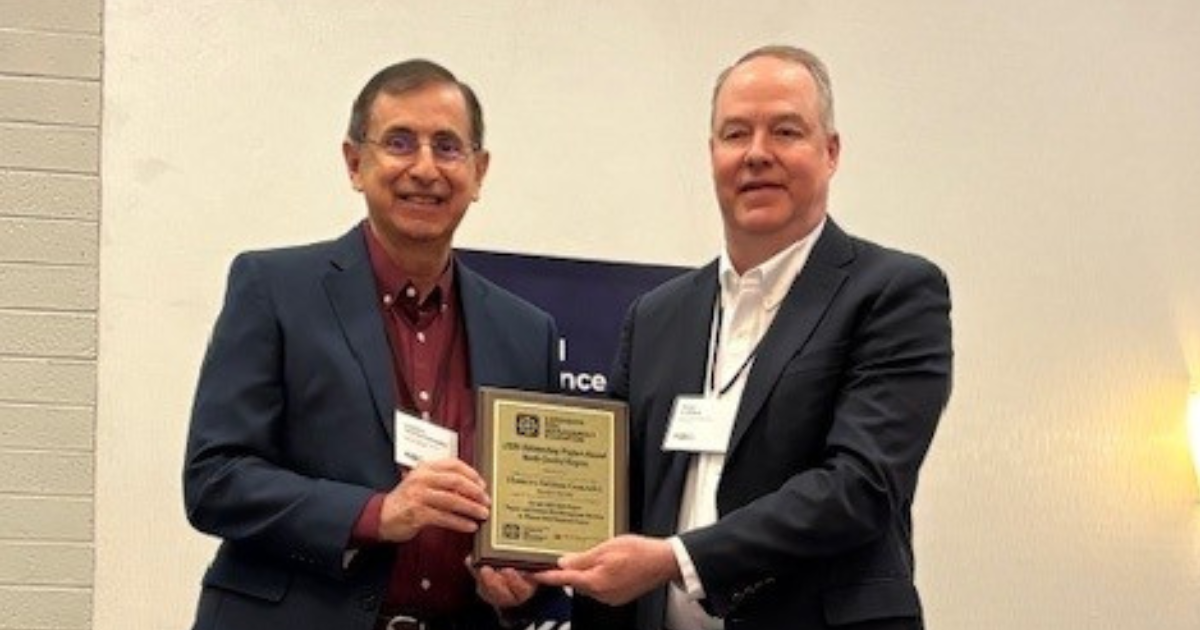 Two men stand together holding an award plaque.