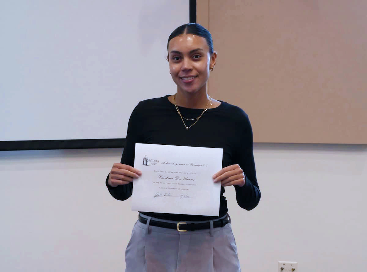 A young woman in professional clothes holds a certificate.