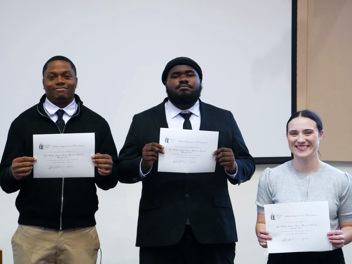 Three students in professional clothing hold certificates.