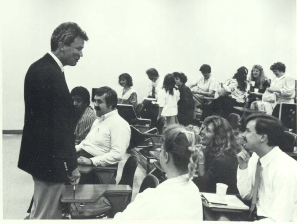 Black and white image of a teacher in a classroom with students in the late 1980s at Lincoln.