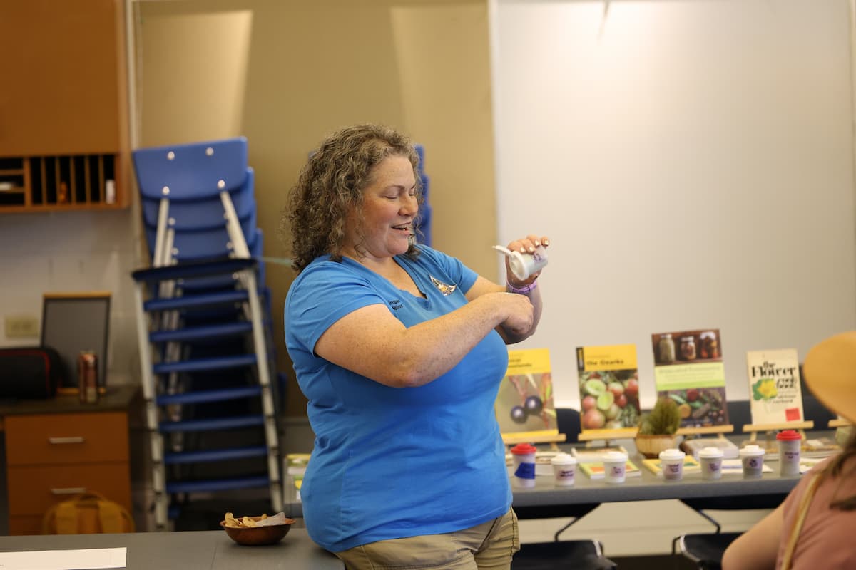 A woman shakes some sugar onto her hand from a small container.