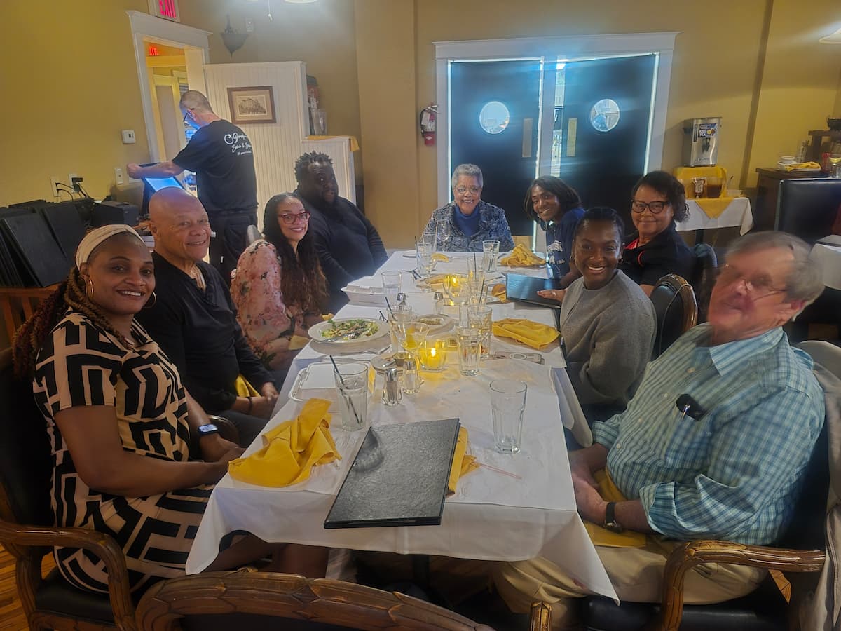 A group of people sit at a dinner table at a restaurant.