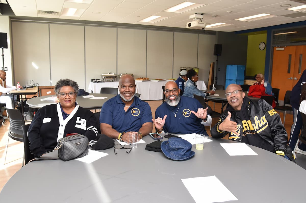 Four Lincoln alumni sit at a table and smile for the camera.
