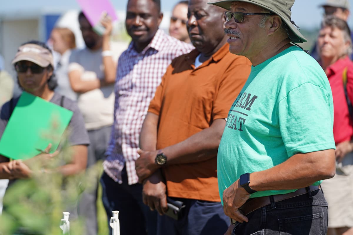 Webster Davis stands in the foreground with a group of attendees beside quinoa research plots at George Washington Carver Farm.