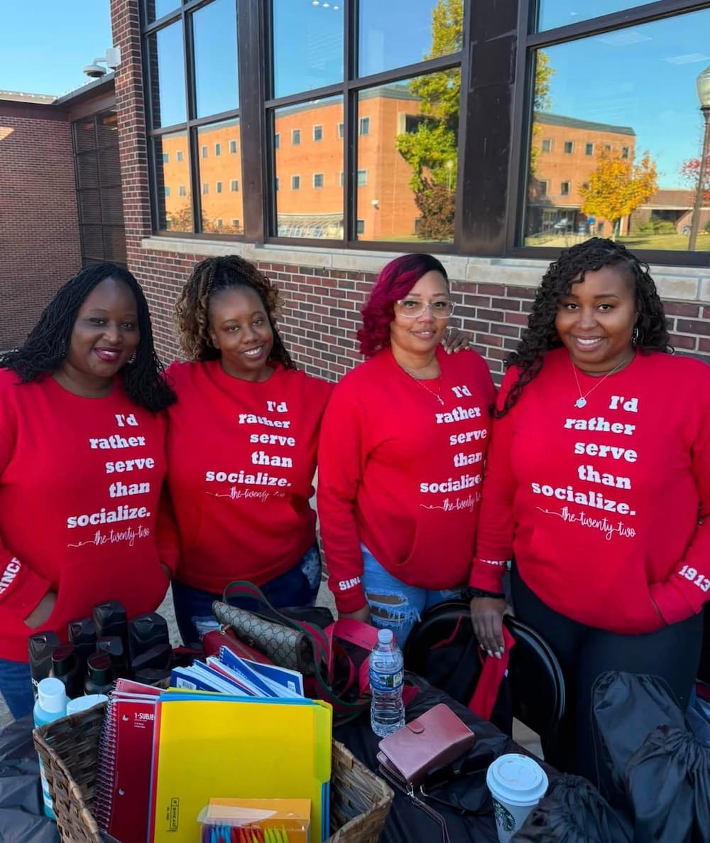 Four women in red sweatshirts smile for a photo.