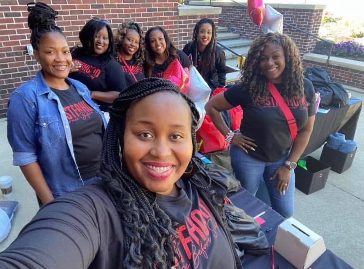 A group of women smile for a photograph while packing up drawstring backpacks.