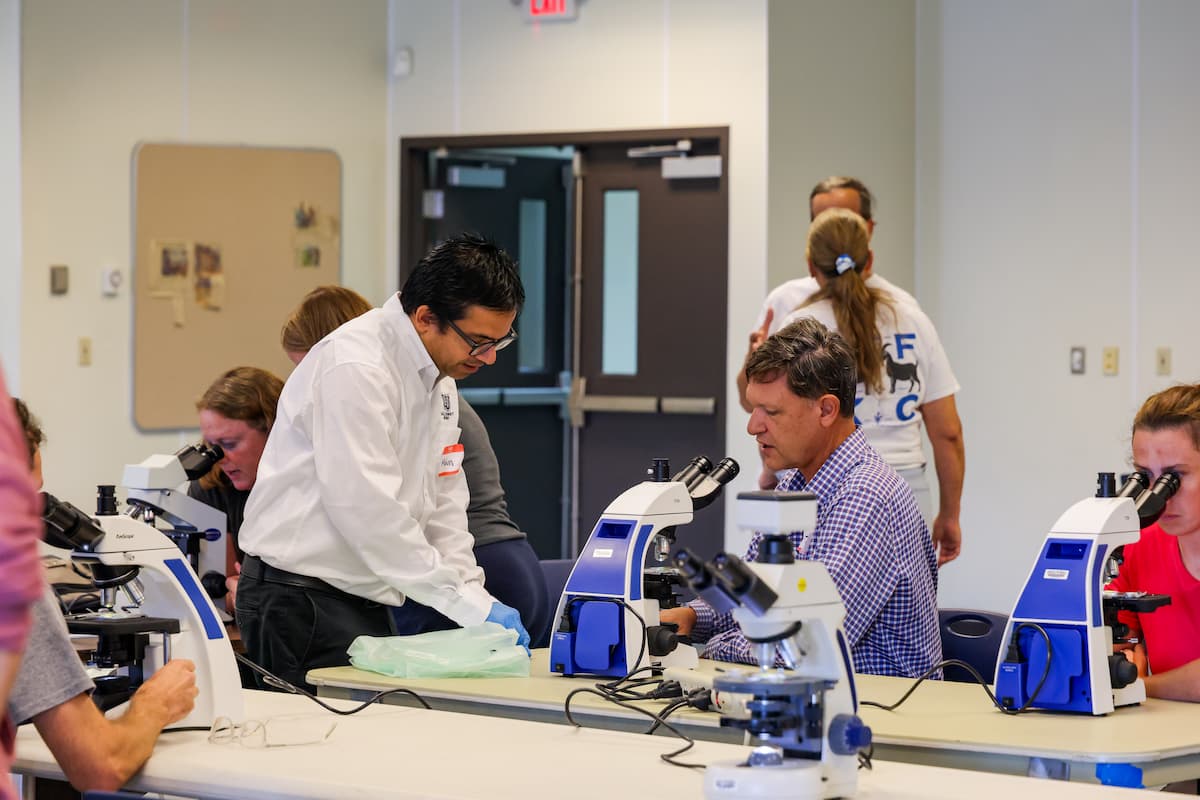 Mohan Acharya works with participants using microscopes during parasite management training.