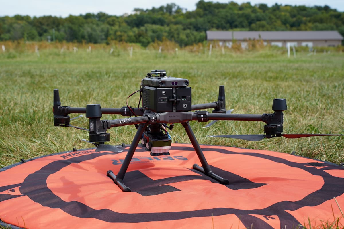 A research drone sits on an orange landing pad in a field at George Washington Carver Farm.