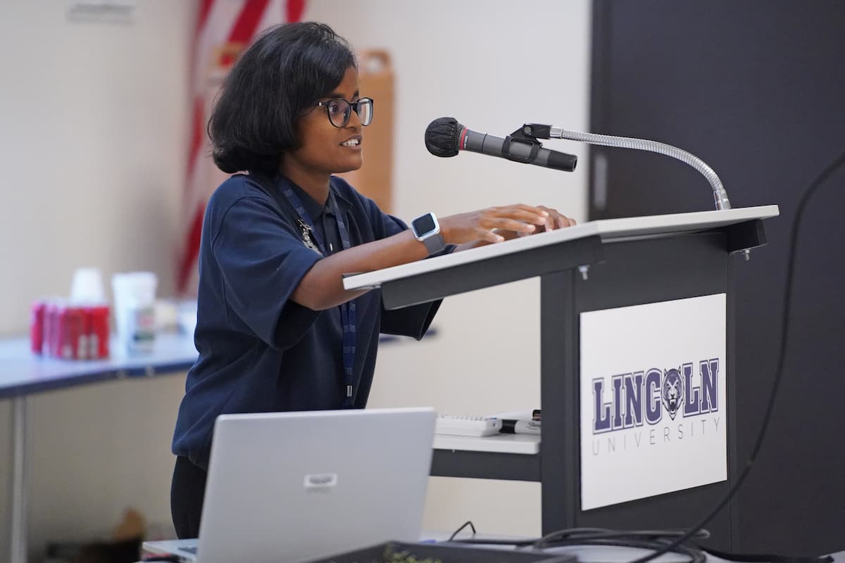 Fatema Tuj Johora speaks at a podium about quinoa research during an LU field day.
