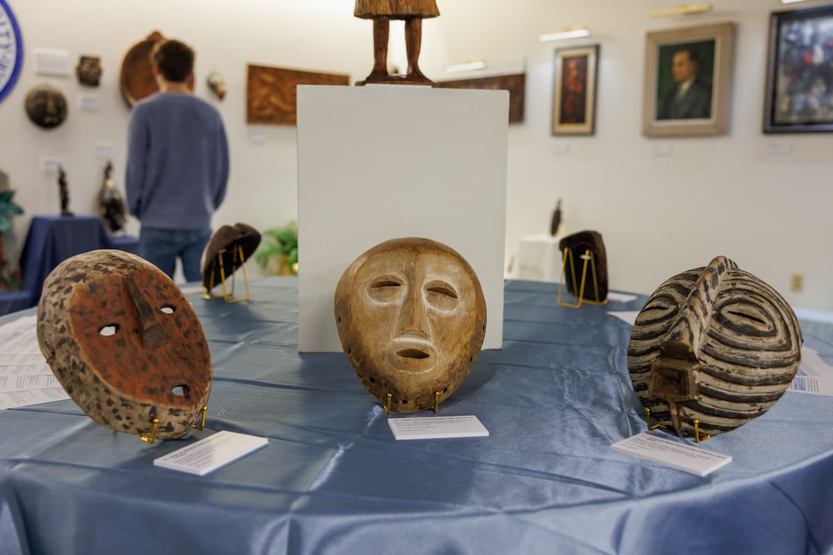 Masks are lined up on an art display.