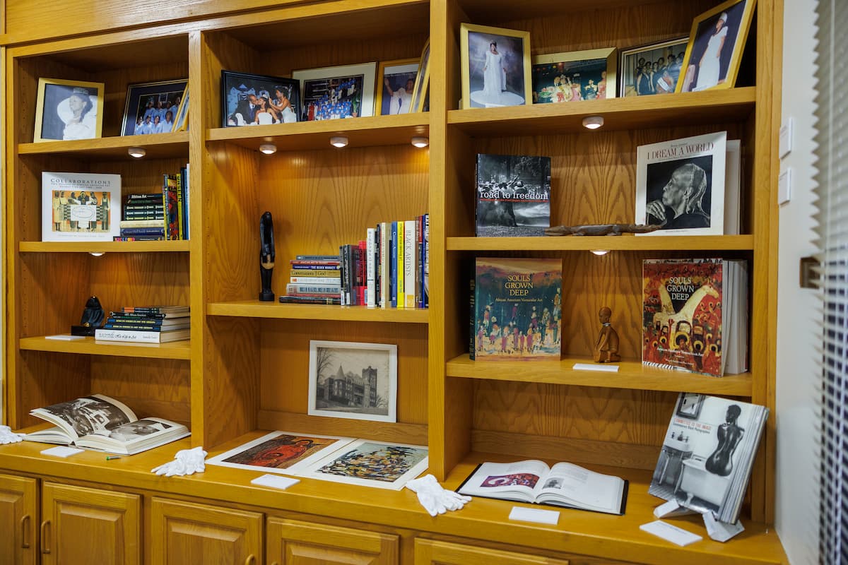 Shelves full of artwork and books are on display at an art exhibit.