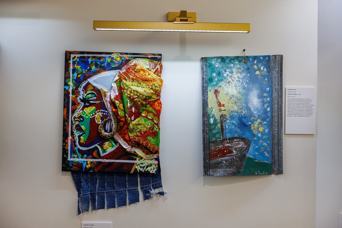 Two colorful paintings hang on the wall at an art exhibit.