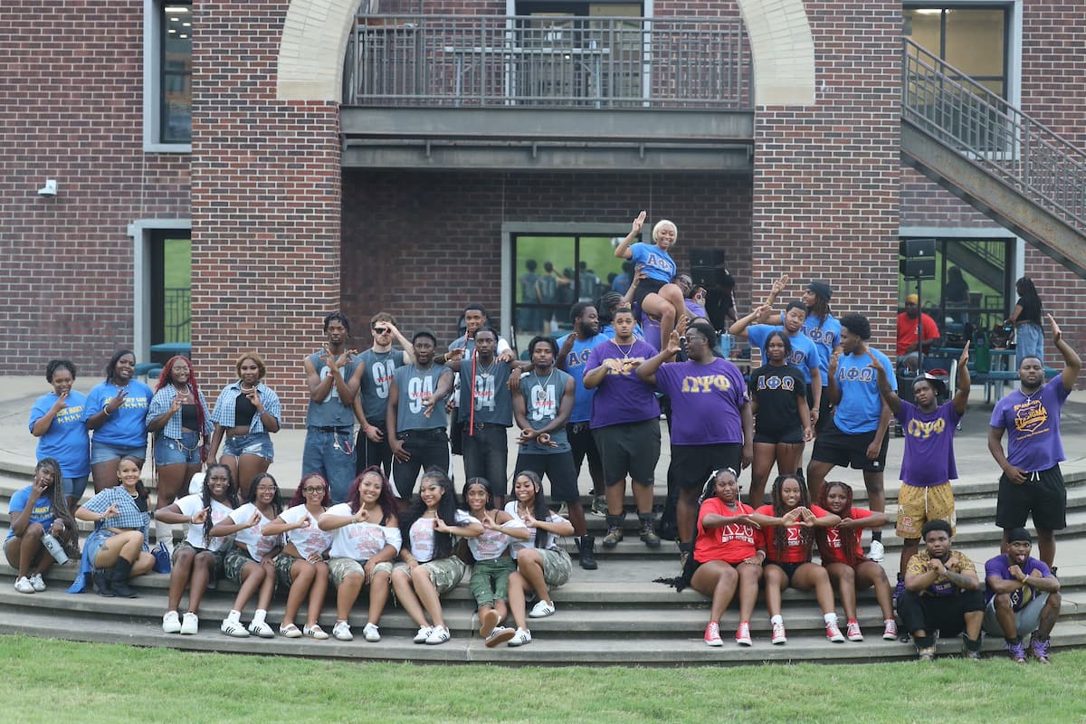 A large group of students and alumni post for a photo outside at the Greek Serenade.
