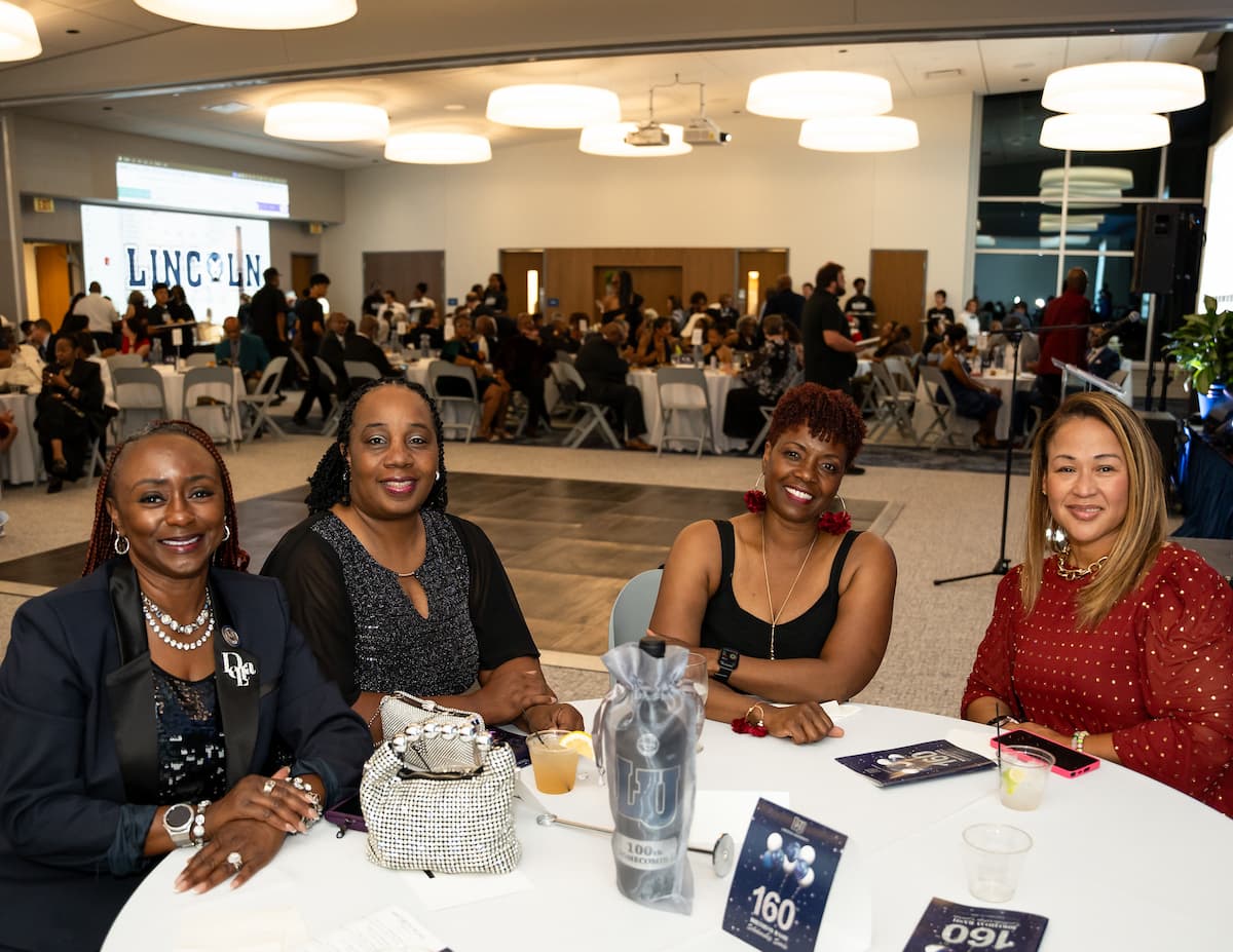 Four women sit at a round table at the Homecoming birthday bash.