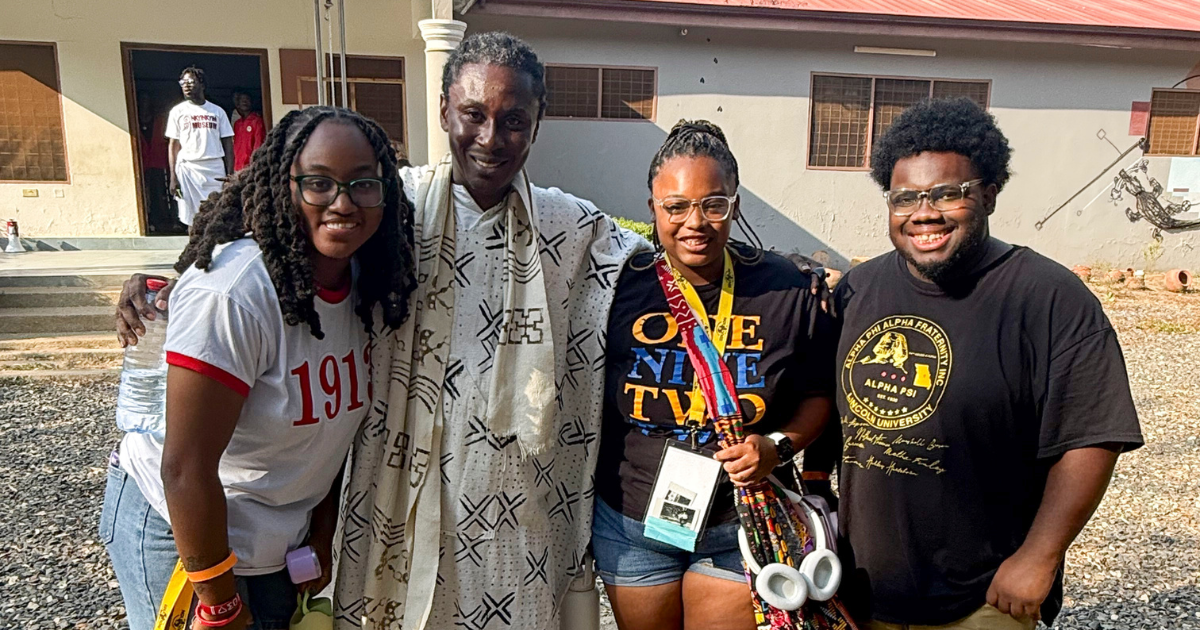 Three Lincoln University students pose for a photo with someone in Ghana at the African Diaspora Education Summit. 