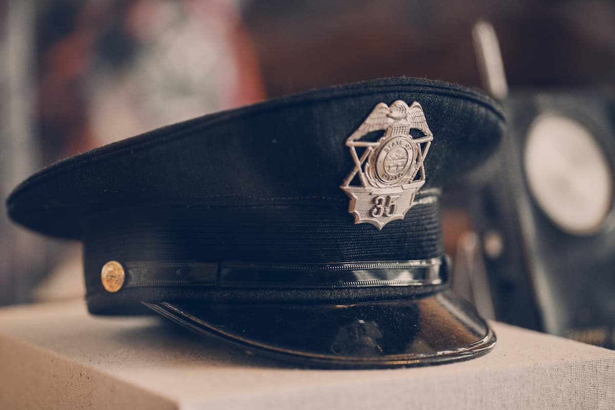 Black police officer's hat with a silver badge marked "35" resting on a surface, symbolizing law enforcement service and duty.