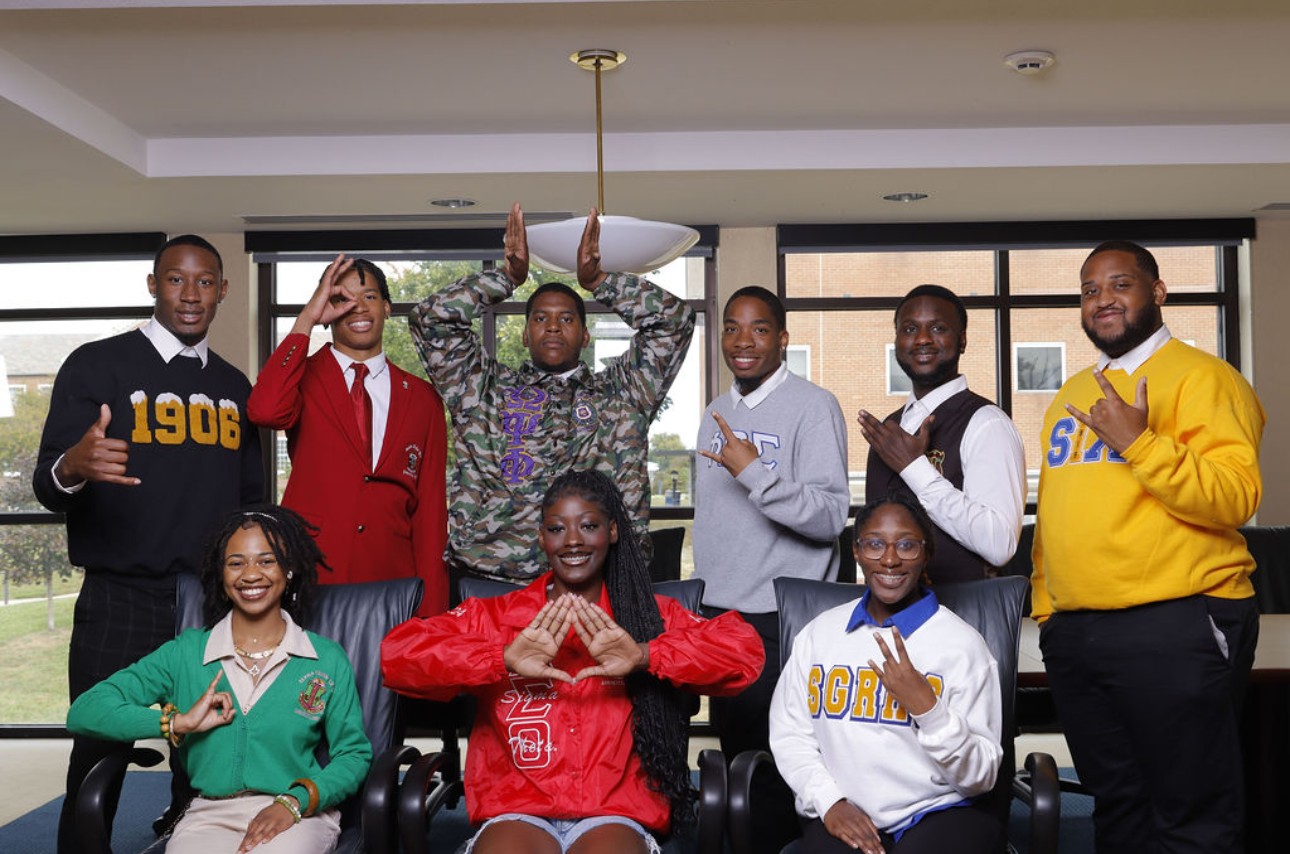 Lincoln University of Missouri representatives of fraternity and sorority life pose for a photo while showing Greek Life signs.